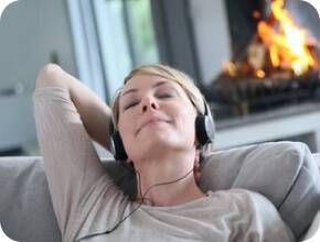 Mulher a ouvir música com auscultadores no sofá