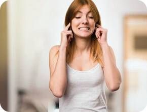 Mulher a tapar os ouvidos por causa do barulho